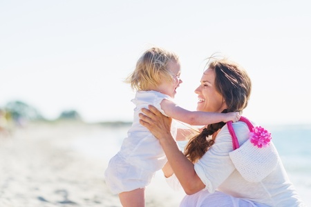 Mother and baby playing on sea shoreの写真素材
