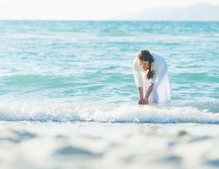 Happy young woman wetting hands in seaの写真素材