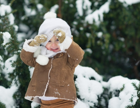 Portrait of happy baby looking out from hat in winter parkの写真素材