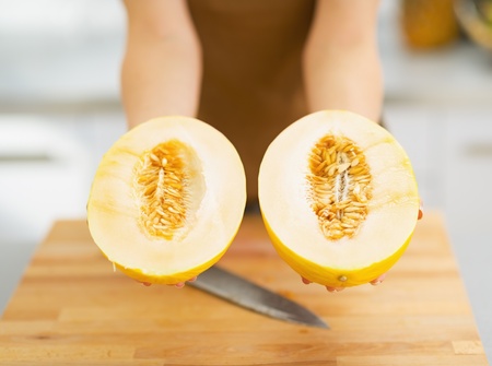 Closeup on two slices of melon in hand of womanの写真素材