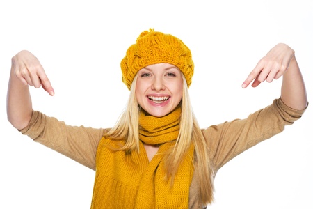 Smiling young woman in hat and scarf pointing down on copy spaceの写真素材