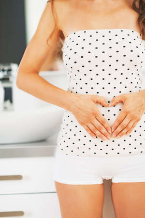Closeup on young woman making heart with hands in bathroomの写真素材