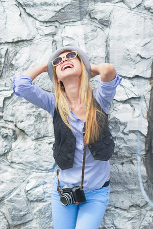 Happy hipster girl rejoicing against rocky wall outdoorsの写真素材