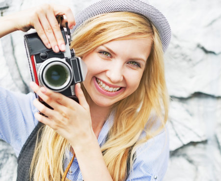 Portrait of smiling hipster girl making photo with retro cameraの写真素材