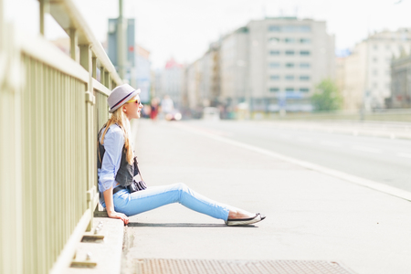 Hipster girl sitting on city streetの写真素材