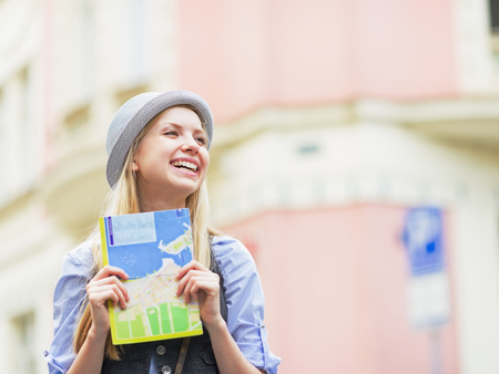 Happy tourist girl with map looking on copy space on city streetの写真素材