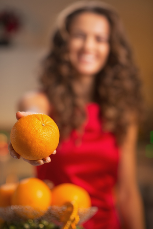 Closeup on orange in hand of young housewife in kitchenの写真素材