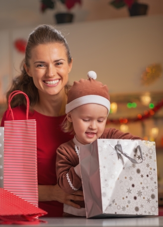 Portrait of happy mother and baby checking christmas shopping bagsの写真素材