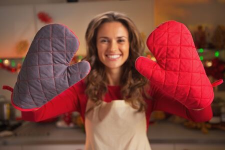Closeup on kitchen gloves showing by young housewife in christmas decorated kitchenの写真素材