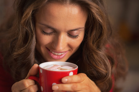 Smiling young woman in red dress having snack in christmas decorated kitchenの写真素材