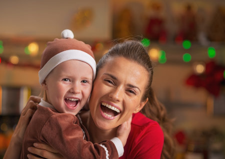 Portrait of smiling mother and baby in christmas decorated kitchenの写真素材