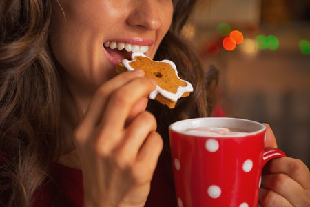 Closeup on young woman eating christmas cookie