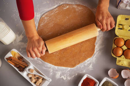 Closeup on young housewife rolling pin dough in kitchenの写真素材