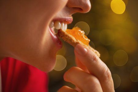 Portrait of young woman eating cookie with orange jam