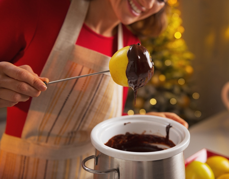 Closeup on happy young housewife making apple in chocolate glaze in christmas decorated kitchenの写真素材