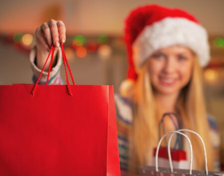 Closeup on smiling teenage girl in santa hat showing shopping bagの写真素材