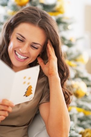 Smiling young woman reading christmas postcardの写真素材