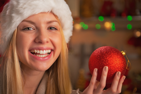Portrait of happy teenage girl in santa hat showing christmas ballの写真素材