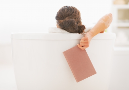 Closeup on young woman in bathtub holding bookの写真素材