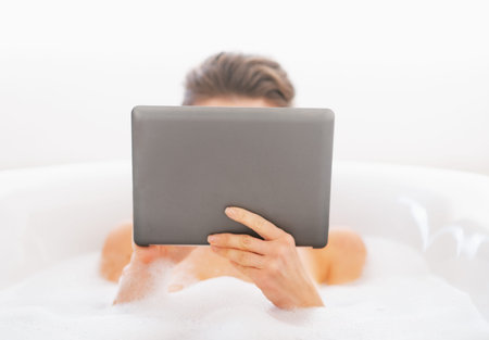 Young woman using tablet pc in bathtub