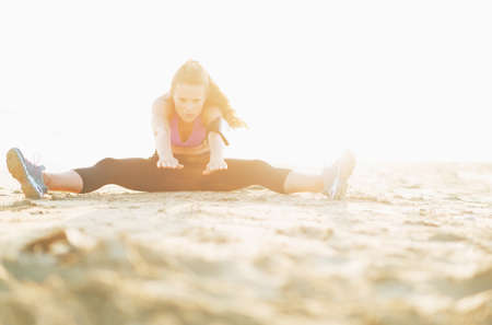 Fitness young woman stretching on beachの写真素材