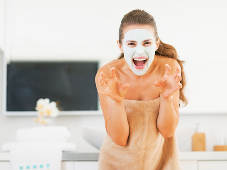 Young woman with cosmetic mask on face scaringの写真素材