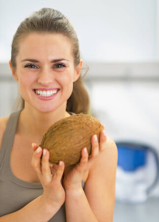 Happy young woman holding coconutの写真素材