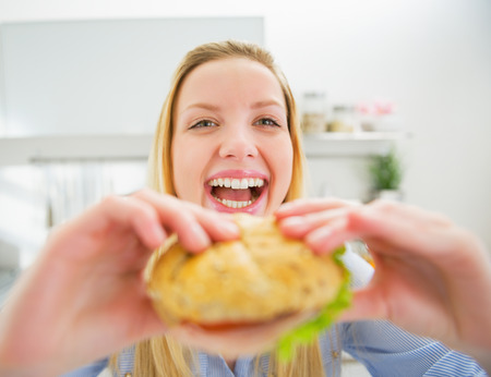 Smiling young woman eating burgerの写真素材
