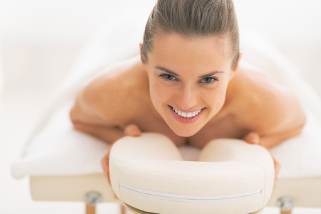 Happy young woman laying on massage tableの写真素材