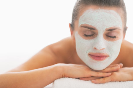 Young woman with revitalising mask on face laying on massage table