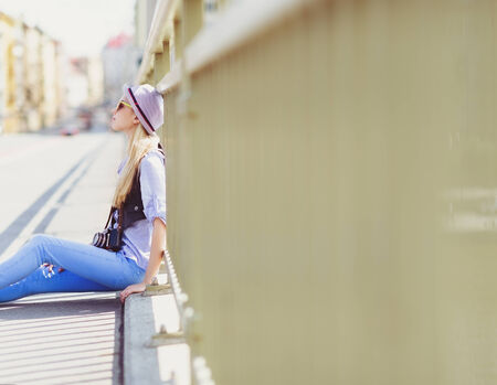 Young hipster sitting on city streetの写真素材