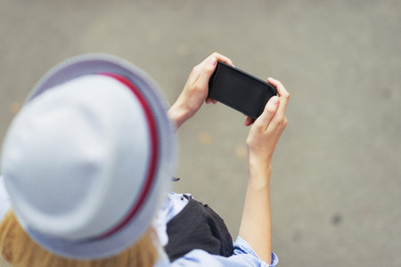 Young hipster writing sms on city street
