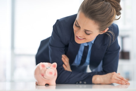 Happy business woman looking on piggy bankの写真素材