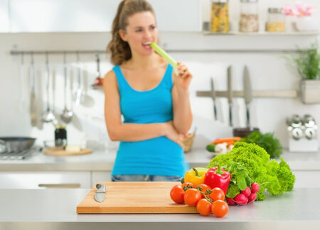 Closeup on fresh vegetables on table and young woman in backgroundの写真素材