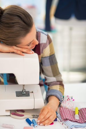 Tired seamstress sleeping on sewing machineの写真素材