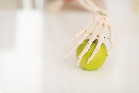 Closeup on human skeleton hand holding appleの写真素材