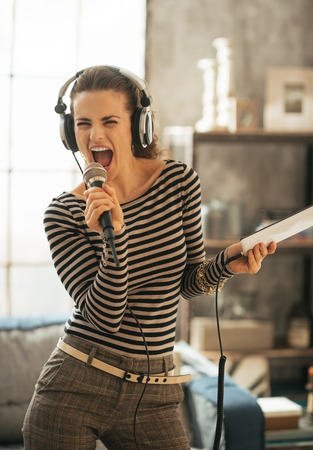 Young woman with tablet pc singing karaokeの写真素材