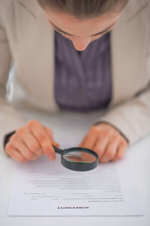 Closeup on business woman exploring document with magnifying lensの写真素材