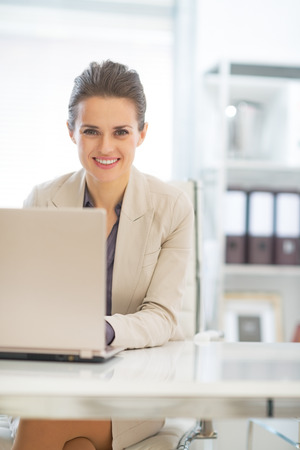 Happy business woman working on laptop in officeの写真素材