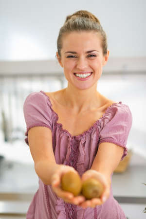 Portrait of happy young housewife showing kiwiの写真素材