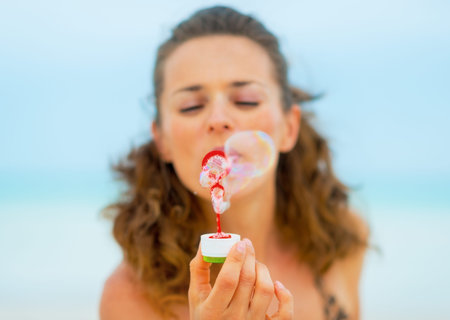 Closeup on young woman blowing soap bubbles on beachの写真素材