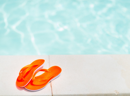 Closeup on sandals laying near swimming poolの写真素材