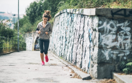 Fitness young woman jogging in the city park. rear view