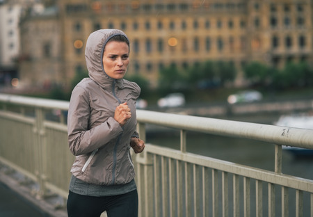Fitness young woman jogging in rainy cityの写真素材