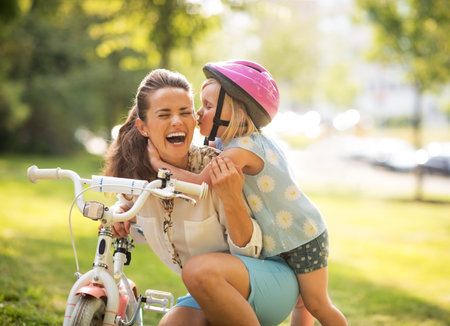 Happy mother and baby girl having fun in park with bicycleの写真素材