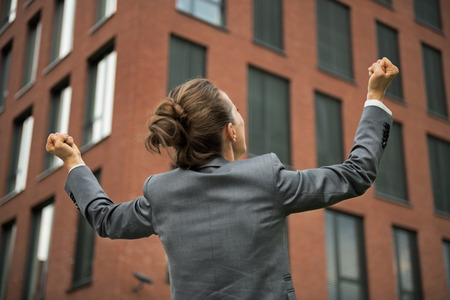 Business woman rejoicing in front of office building. rear viewの写真素材