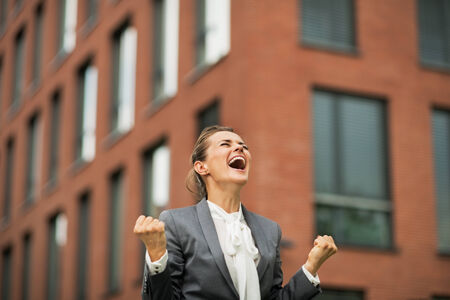 Happy business woman rejoicing in front of office buildingの写真素材