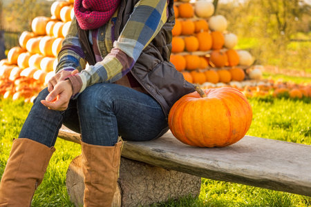 Closeup on happy young woman sitting with pumpkin in front of pumpkin piramideの写真素材