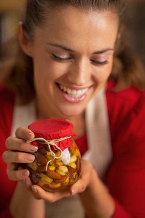 Portrait of happy young housewife holding jar with honey nutsの写真素材