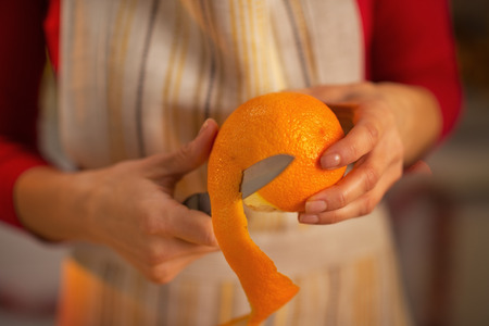 Closeup on young housewife removing orange peelの写真素材